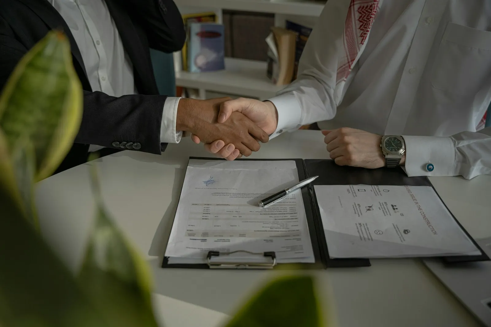 Two professionals shaking hands over documents